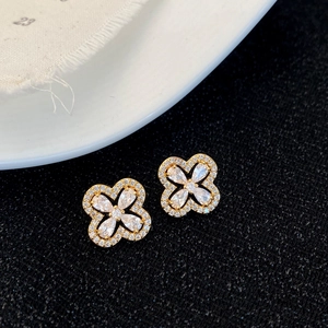 Détail macro de boucles d'oreilles trèfle dorées avec des zircons de coupe poire