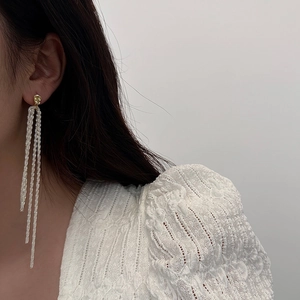 Long tassel drop earrings with golden lava texture studs worn by a model