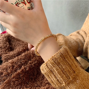 Minimalist gold textured bangle with sparkling stardust finish on a woman's wrist