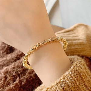 Macro view of gold minimalist open cuff bracelet with irregular textured hammered finish
