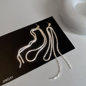 Elegant long gold and silver tassel fringe drop earrings on a black jewelry display card
