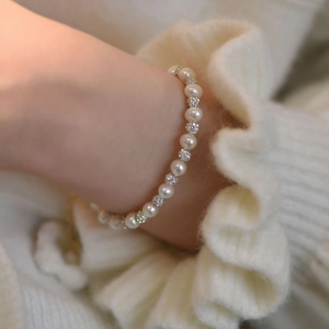 Close-up of elegant freshwater pearl bracelet with rhinestone pavé balls on knit sleeve