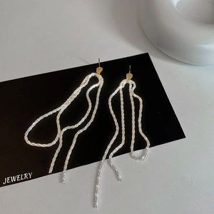Detailed close-up of long gold and silver tassel earrings with shimmering rhinestones