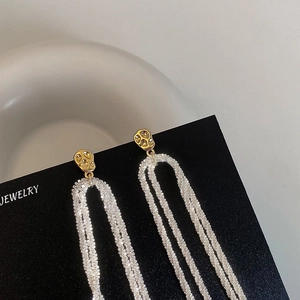 Detail of long fringe earrings featuring gold hammered studs and silver mesh tassels