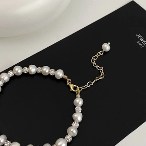 Detail of freshwater pearl bracelet with gold lobster clasp and heart-shaped extender chain