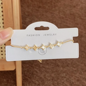 Elegantes goldenes Armband mit fünf Muschel-Sternanhängern auf einer Displaykarte