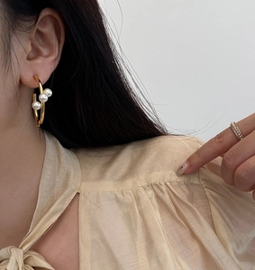 Gros plan sur des boucles d'oreilles dorées en C avec perles et bague assortie