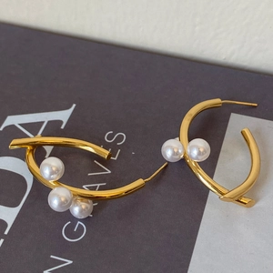 Gros plan de boucles d'oreilles dorées en C avec trois perles sur magazine