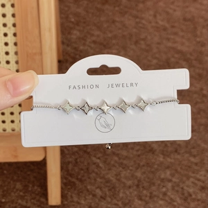 Verstellbares Silberarmband mit fünf weißen Muschel-Sternanhängern auf Displaykarte