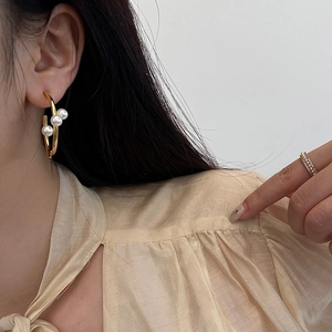 Ensemble élégant de boucles d'oreilles et bague en perles dorées porté par un mannequin