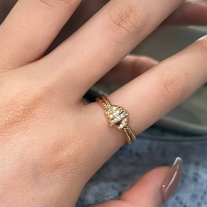Close-up of double-layer woven gold ring with pavé diamond knot worn on a finger