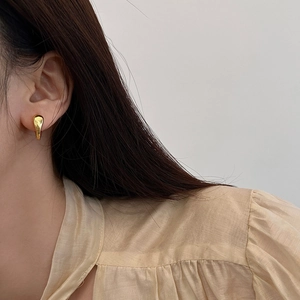 Minimalist gold teardrop earrings for women featuring a polished metallic finish on ear