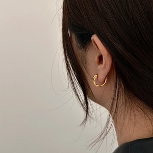 Close-up of minimalist gold oval hoop earrings with high-polish finish on a model