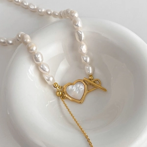 Détail macro du collier de perles avec pendentif cœur en or et fermoir à bascule OT