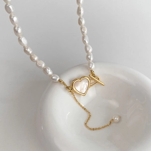 Détail du collier de perles baroques avec pendentif cœur et fermoir à bascule doré