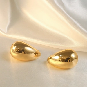 Detailed view of teardrop earrings with gold plating on elegant beige silk fabric