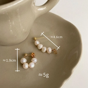 Detailed view of freshwater pearl drop earrings with size markers on a ceramic saucer