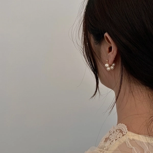 Detail shot of French style cluster freshwater pearl earrings on model with gold accents
