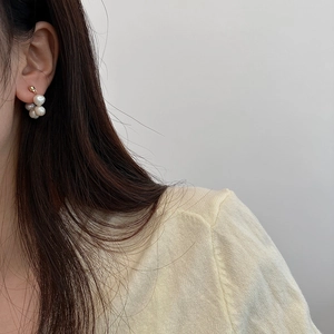 Close-up of a delicate baroque pearl cluster earring with elegant gold metal accents