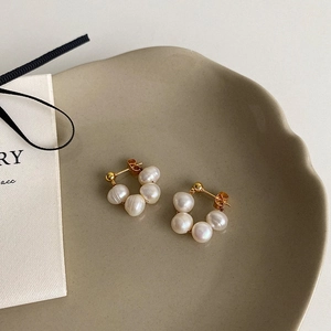 Detailed close-up of gold hoop earrings with five white baroque freshwater pearls