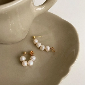 Detail of natural freshwater pearl earrings in gold setting on a ceramic dish