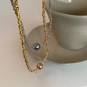 Detail of gold and silver beaded necklaces with elegant pearls on a ceramic cup