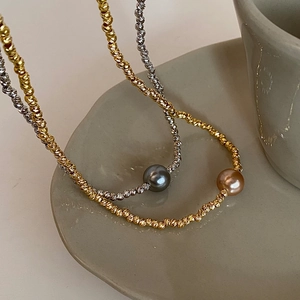 Detailed close-up of faceted metal bead necklaces with champagne and grey pearls