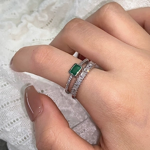 Detail of emerald cut green gemstone ring set with sparkling zircon on silver band