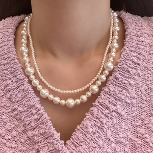 Gros plan d'un élégant collier de perles à double rang sur un pull violet pour femme