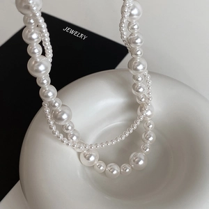 Vue détaillée d'un élégant collier de perles à double rang sur un vase blanc