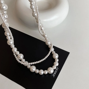 Gros plan du collier de perles double épaisseur style français avec reflets rétro et or
