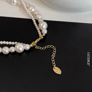 Détail d'un collier de perles à double rangée avec fermoir mousqueton doré et extension