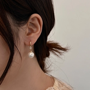 Détail macro de boucles d'oreilles vintage avec perle et zircon sur métal doré