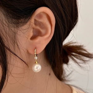Gros plan d'une boucle d'oreille vintage en perle et zircon sur l'oreille