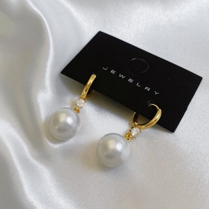 Détail des boucles d'oreilles perles vintage avec accents zircon sur métal doré
