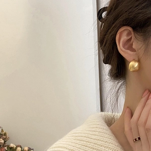 Primo piano di orecchini a fagiolo in oro opaco e anello in smalto rosso