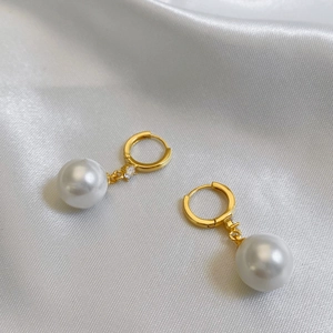 Détail de boucles d'oreilles perles avec zircones sur fond de soie blanche