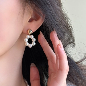 Gros plan de boucles d'oreilles boules dorées avec pendentif circulaire en perles d'eau douce