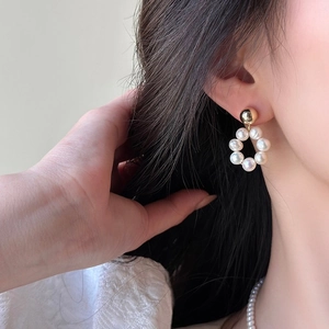 Détail de boucles d'oreilles créoles dorées avec perles d'eau douce sur un mannequin femme