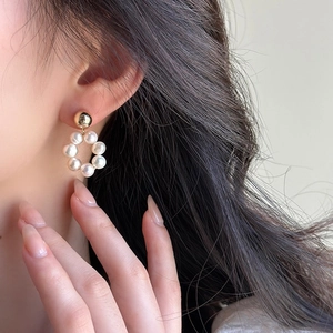 Vue rapprochée de boucles d'oreilles circulaires en perles d'eau douce avec détails dorés