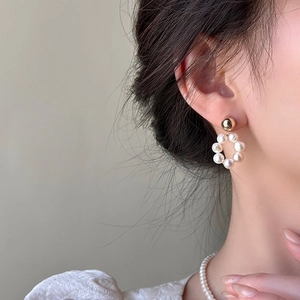 Gros plan de boucles d'oreilles élégantes en perles d'eau douce avec clou doré sur modèle