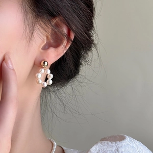 Élégantes boucles d'oreilles boules dorées avec pendentifs perles d'eau douce sur modèle
