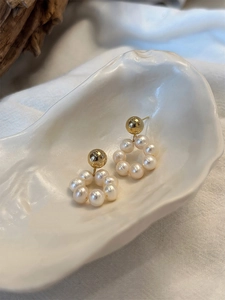 Gros plan de boucles d'oreilles en perles d'eau douce sur un plateau coquillage