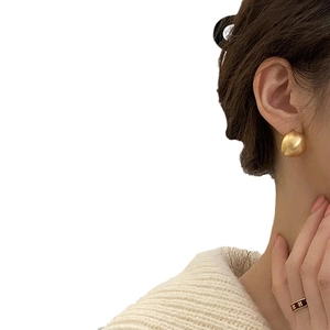 Orecchini a perno curvi a fagiolo in oro opaco minimalisti indossati da modella