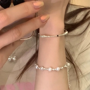 Détail d'un bracelet superposé en perles d'eau douce et perles argentées au poignet