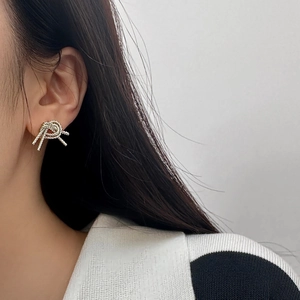 Detail shot of silver double-layered bow stud earrings with twisted knot texture