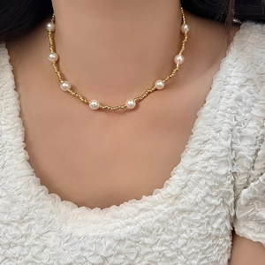 Élégant collier chaîne torsadée dorée avec perles blanches rondes porté par un mannequin