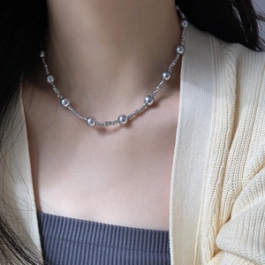 Gros plan d'un collier minimaliste avec perles et billes en métal argenté