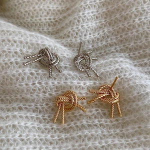 Elegant woven knot stud earrings set in gold and silver finish on knit fabric