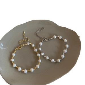 Bracelets élégants en perles d'eau douce dorés et argentés sur plateau céramique